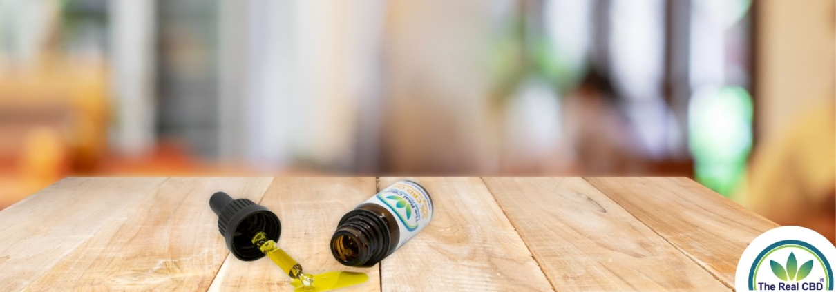 Botella de CBD volcada con aceite derramado sobre una mesa de madera