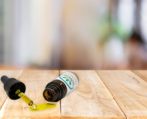 Botella de CBD volcada con aceite derramado sobre una mesa de madera