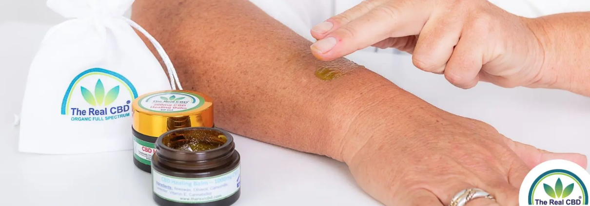 Mano aplicando bálsamo de CBD en el brazo