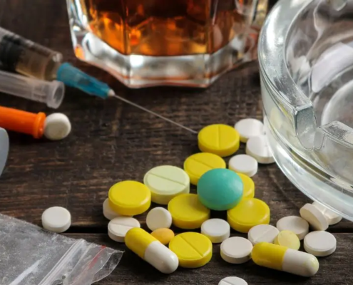 Cenicero con drogas, alcohol y pastillas alrededor