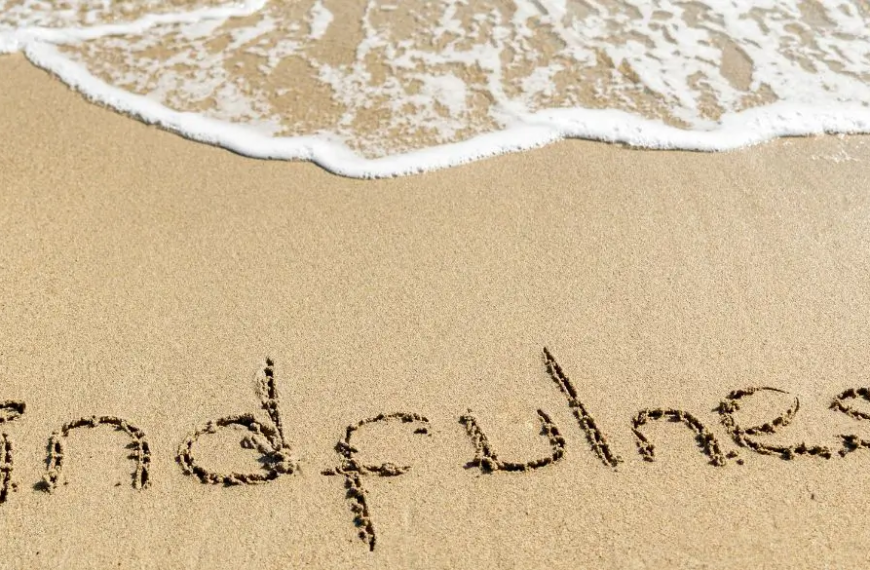 Orilla del mar con MINDFULNESS escrito en la arena