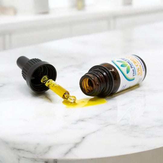 botella de CBD volcada sobre tapa de mármol