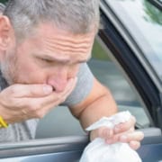 Hombre vomitando por la ventanilla de un coche