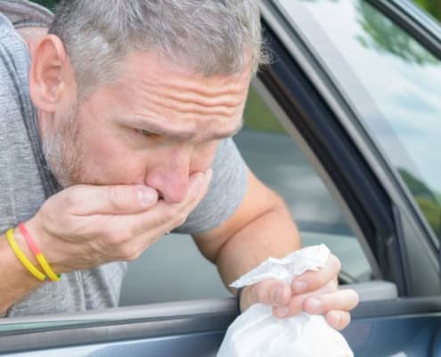 Hombre vomitando por la ventanilla de un coche
