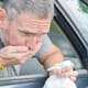 Hombre vomitando por la ventanilla de un coche