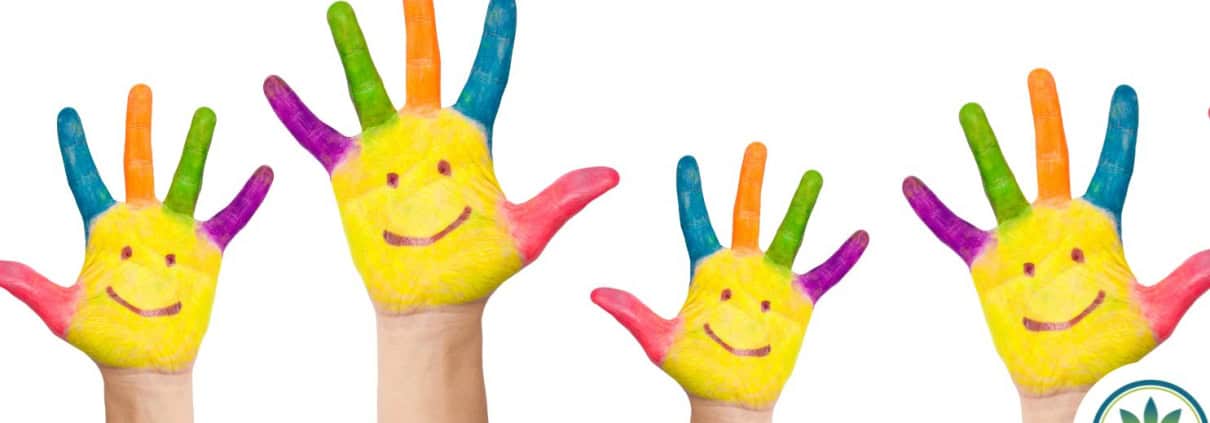 Una hilera de manos infantiles pintadas con caritas sonrientes