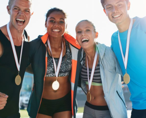 4 atletas con medallas colgadas del cuello con cara de felicidad
