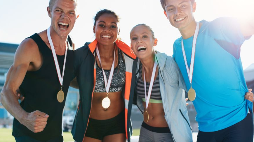 4 atletas con medallas colgadas del cuello con cara de felicidad