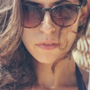 the-real-cbd-blog-experencias-Sarah Sarah en la playa con el viento en el pelo y gafas de sol puestas.