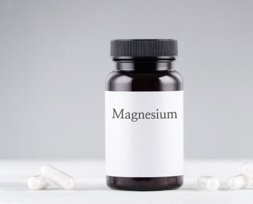 A bottle of CBD oil and a jar of magnesium tabletsUna botella de aceite de CBD y un frasco de comprimidos de magnesio.