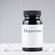 A bottle of CBD oil and a jar of magnesium tabletsUna botella de aceite de CBD y un frasco de comprimidos de magnesio.