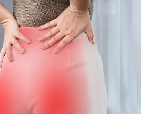 Mujer sujetándose la zona lumbar con dolor.
