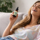 Mujer sentada en un sofá con una botella de aceite de CBD, con aspecto muy feliz y colocada.