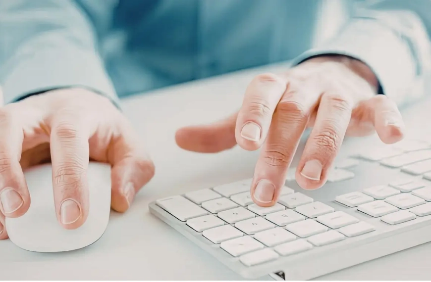Manos manejando el teclado y el ratón de un ordenador