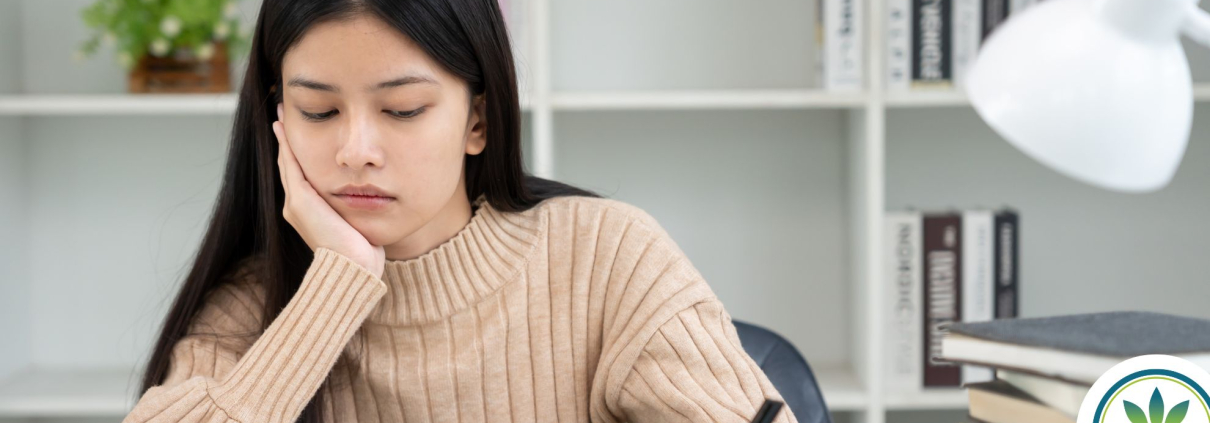 Mujer sentada ante un escritorio con aspecto cansado y ansioso