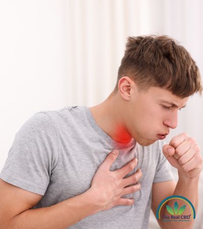 Un hombre con tontallitis que tose con la mano en la boca, con cara de dolor