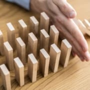 The-Real-CBd-Blog-warum-solltest-du-CBD-vorbeugend-verwenden Hand, die verhindert, dass Holzziegel wie Dominosteine fallen