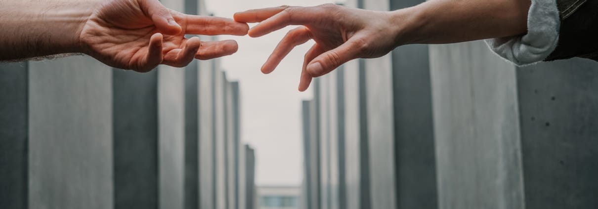 Twee handen reiken en raken elkaar over gebouwen heen