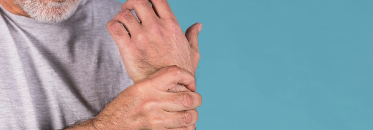Mann hält sein Handgelenk vor Schmerzen