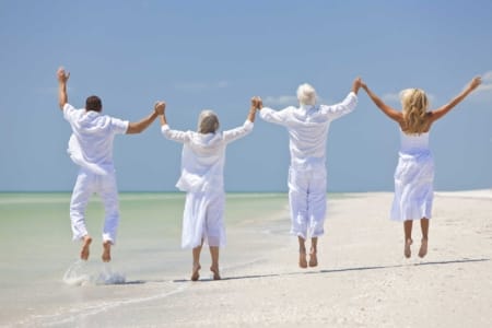 the-real-cbd-organic-full-spectrum-pure-cbd-oil-products-spain-uk-denmark-elderly people-beach-order-cbd-cbg-online 4 personnes heureuses se tenant par la main et sautant sur la plage
