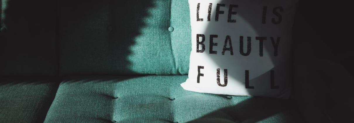 Groene bank met een wit kussen met de tekst "Life is beautiful".