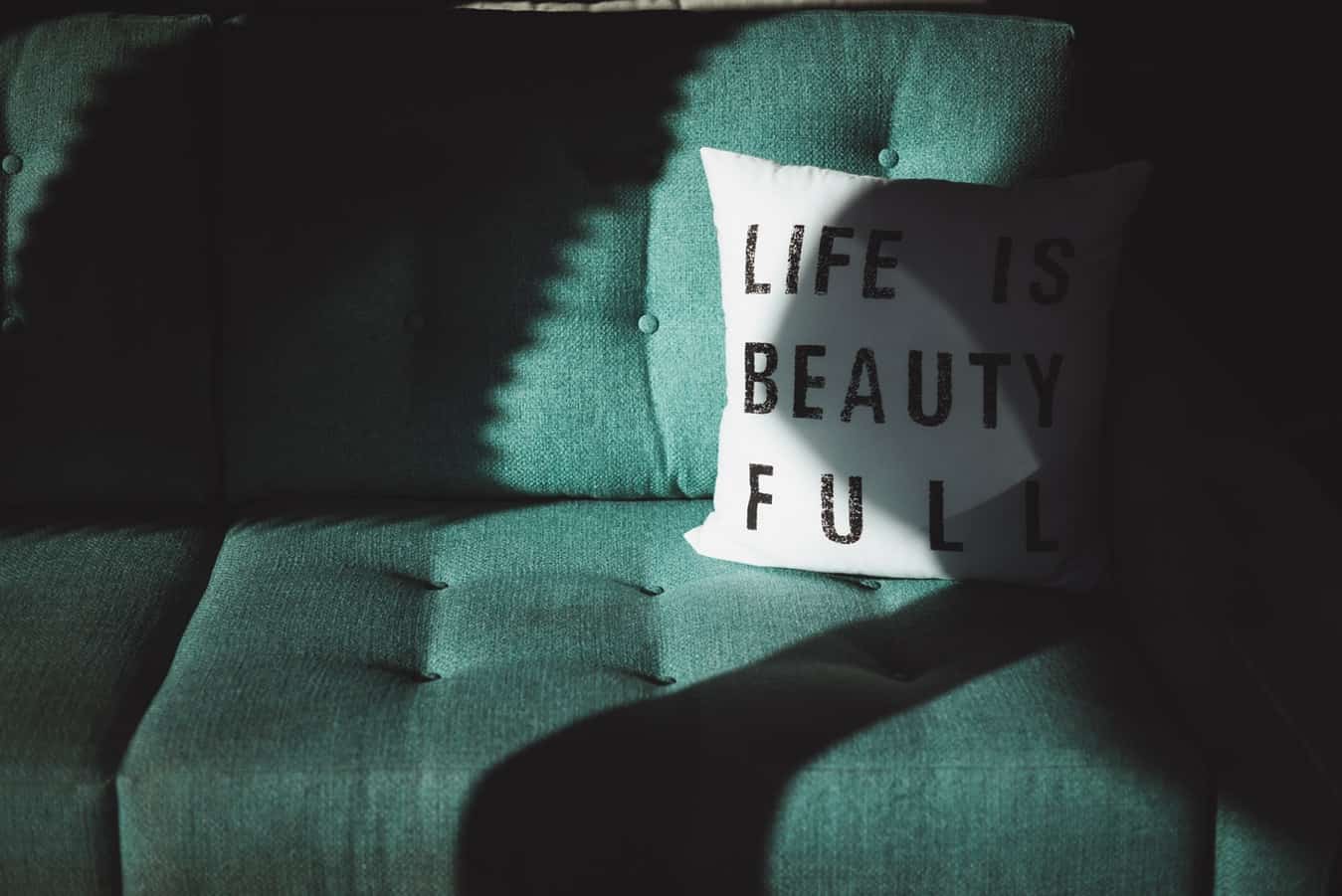 Groene bank met een wit kussen met de tekst "Life is beautiful".
