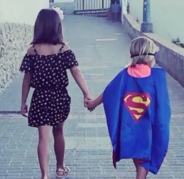 Meisje dat handen met kind superman houdt