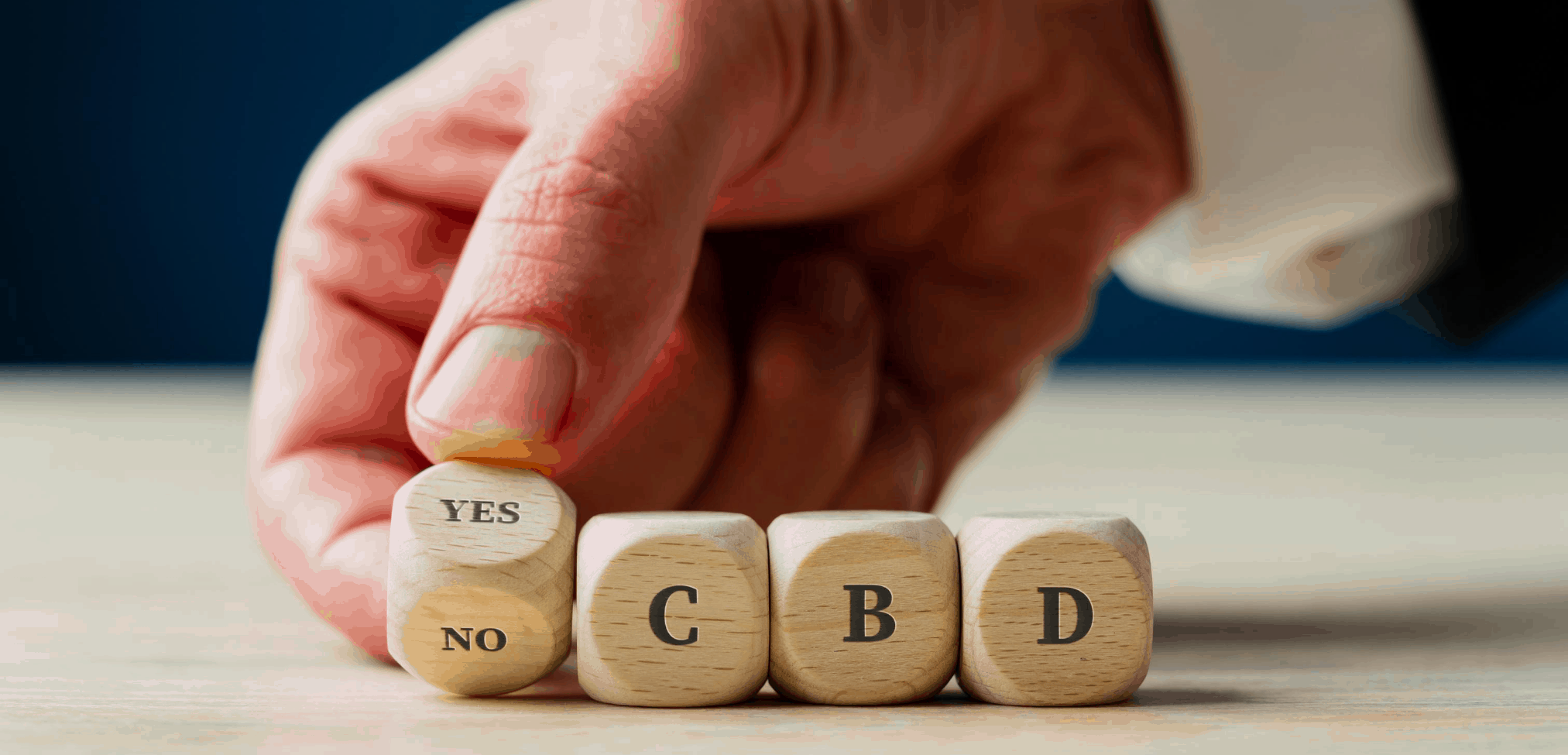 Mann buchstabiert mit der Hand YES CBD in Holzwรผrfeln