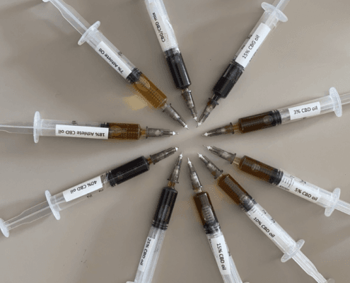 10 syringes with different CBD oil laid out in a circle, demonstrating the colour difference