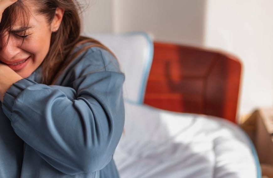 Crying girl sitting on a bed
