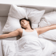The Real CBD Blog Does CBD oil make you sleepy Smiling woman waking up in a bed with white bedsheets