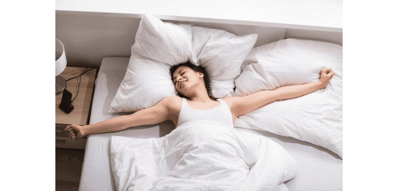 Glimlachende vrouw die wakker wordt in een bed met witte lakens