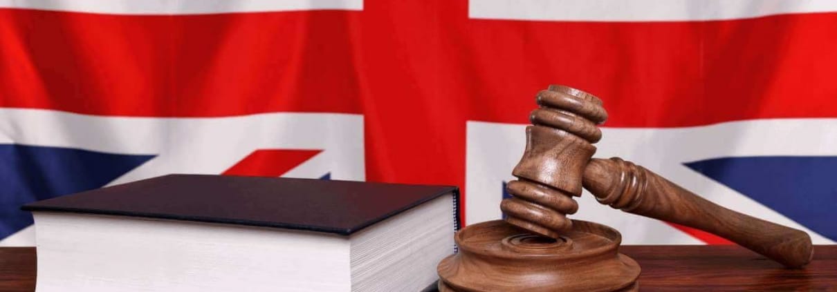 Richterhammer und ein Gesetzbuch vor der britischen Flagge