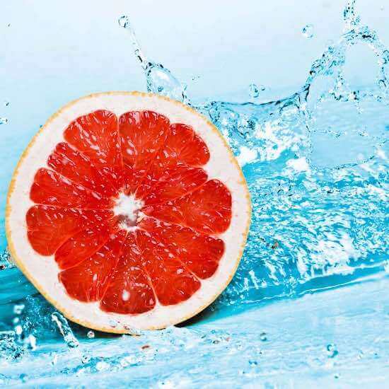 Halved grapefruit in blue water splash