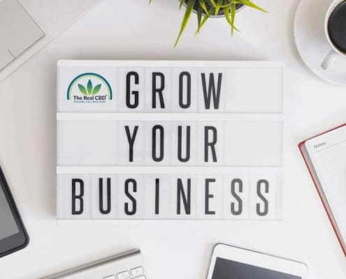 Bürotisch mit Computer, Telefon, Kaffeetasse, Notizbuch und einem Schild mit der Aufschrift "Grow your business".