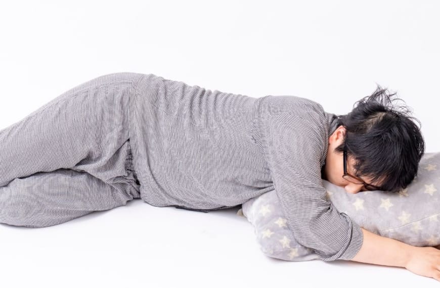 Person sleeping on the floor in grey pyjamas