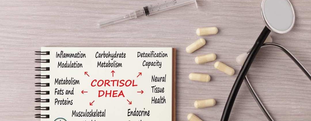 Cortisol DHEA op een briefje op een tafel met capsules, een spuit en een stethoscoop