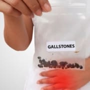 The-Real-CBD-Blog-CBD-for-gallbladder-conditions Person holding a bag of gallstones while holding his pelvis in pain