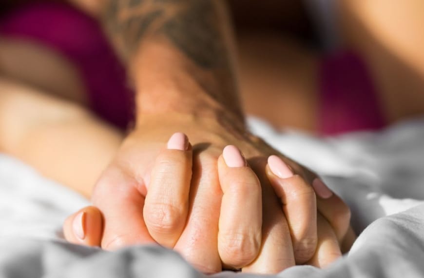 Couple holding hands passionately in bed