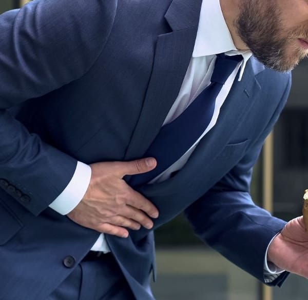 Man met voedsel in de hand buigt voorover van de pijn
