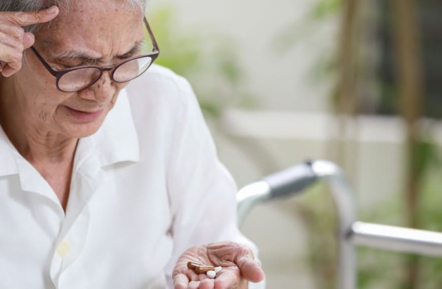 Oudere persoon kijkt verward naar tabletten in hand