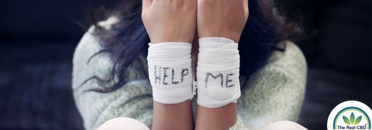 Une femme avec des bandages sur les poignets crie HELP ME