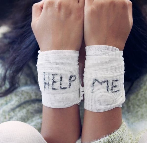 Vrouw met verband om haar polsen spelt HELP ME