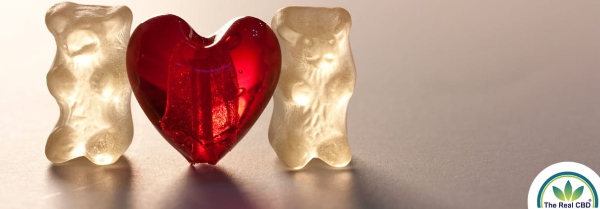 Zwei weiße Gummibärchen mit einem roten Gummiherz dazwischen