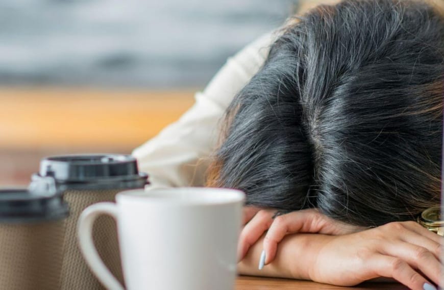 Vrouw slaapt op tafel met veelvoud van koffiekopjes op