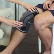 The-Real-CBD-Blog-CBD-after-hip-and-knee-replacement Infirmière tenant le genou malade d'un patient assis