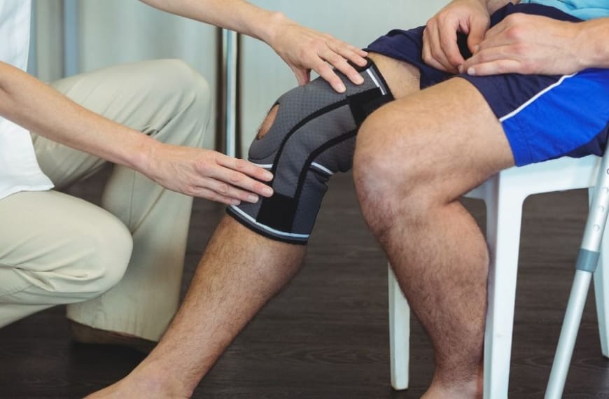 Nurse holding sick knee on patient sitting down