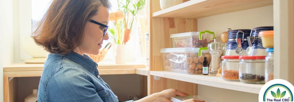 Vrouw in voorraadkast met producten en CBD-olie op de plank