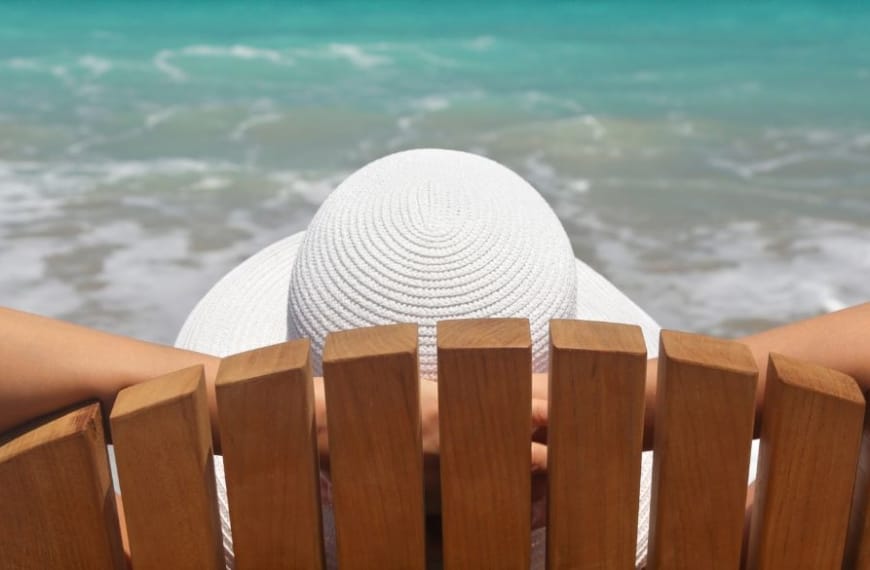 Femme assise sur une chaise de plage au bord de la mer, en train de se détendre