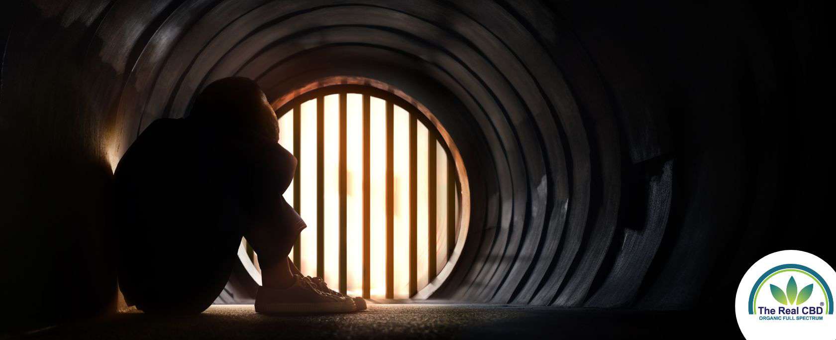 Persoon zittend in een tunnel met het hoofd tussen de knieรซn